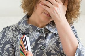 クレジットカードを持ちながら悔しがる女性