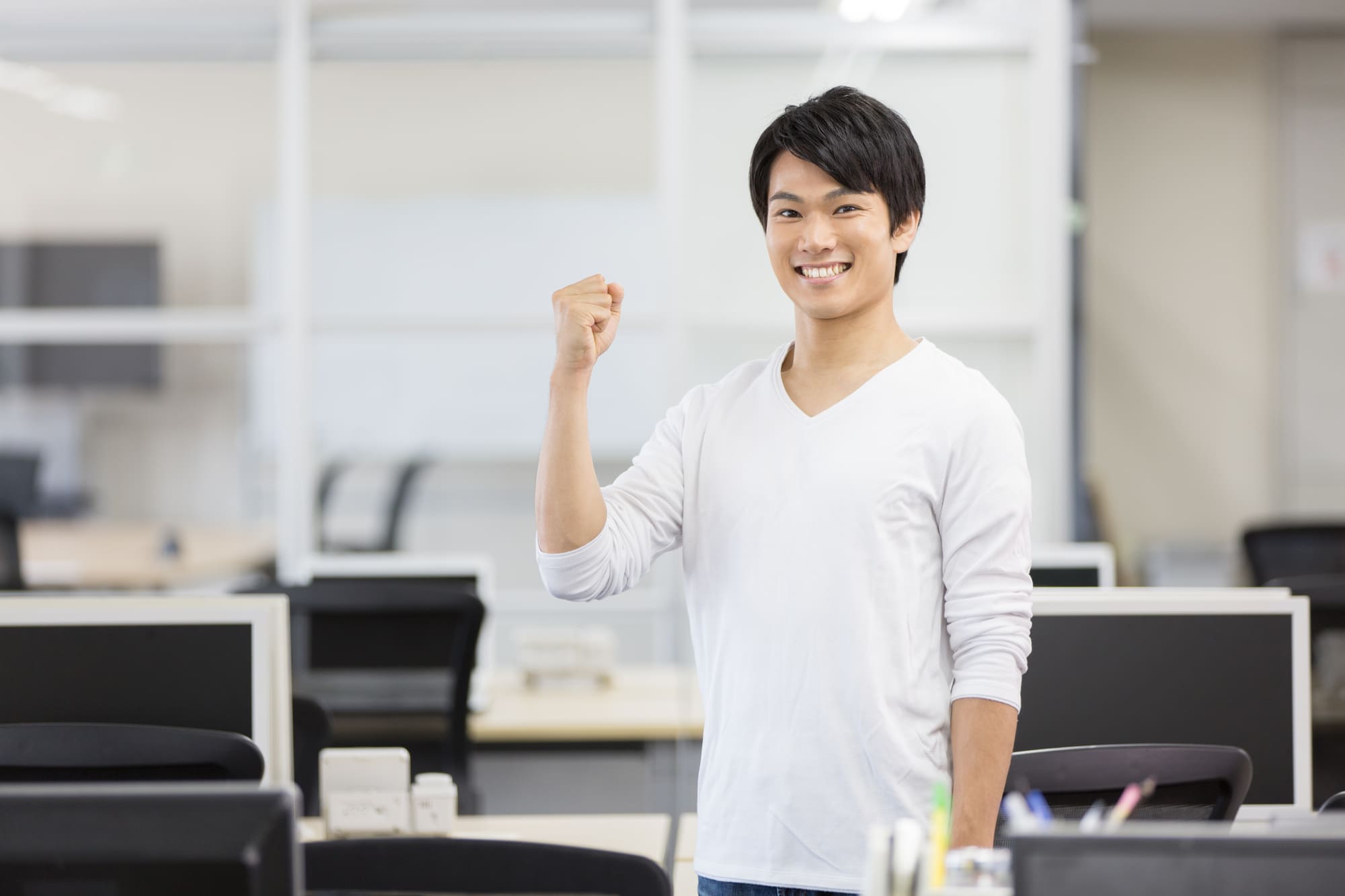 オフィスでガッツポーズをして微笑む男性