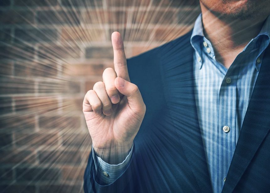 人差し指を立てるスーツ姿の男性
