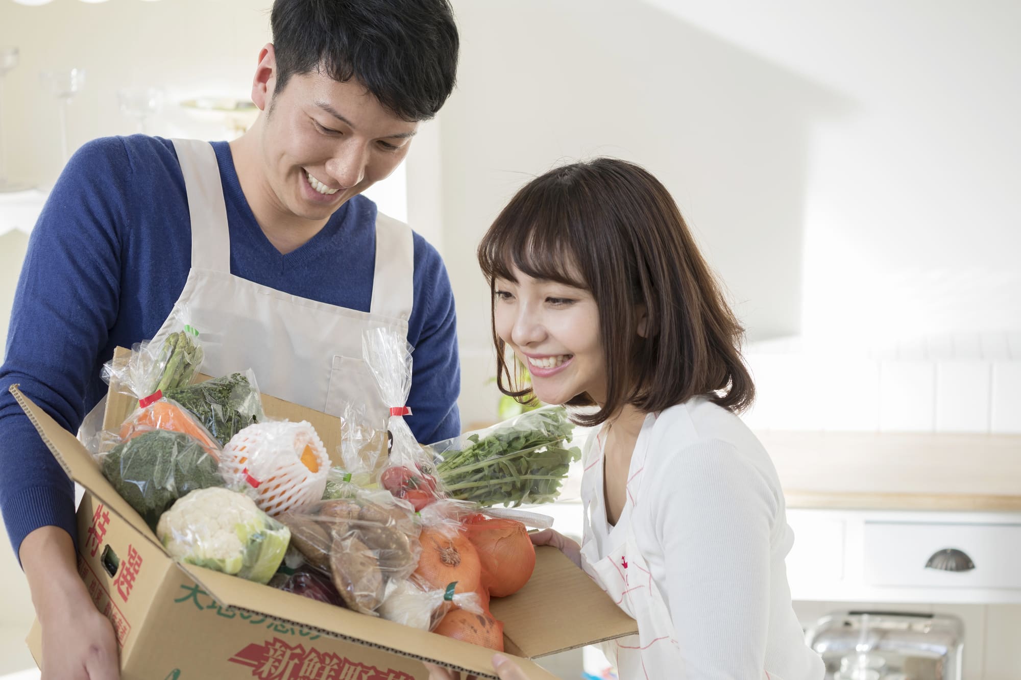 野菜がたっぷりはいた箱をみて喜ぶ夫婦