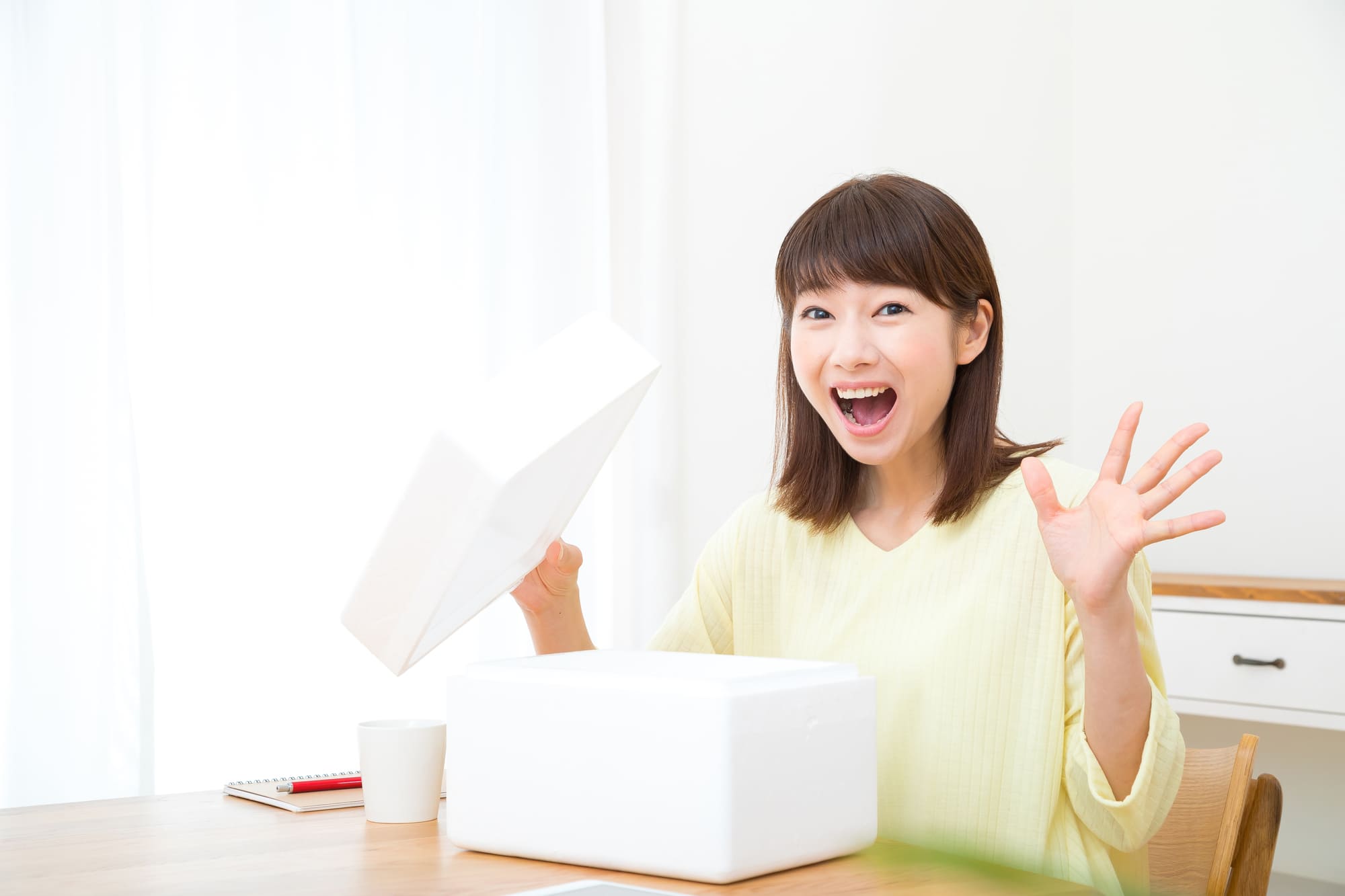 白い箱の中身を見て喜ぶ女性