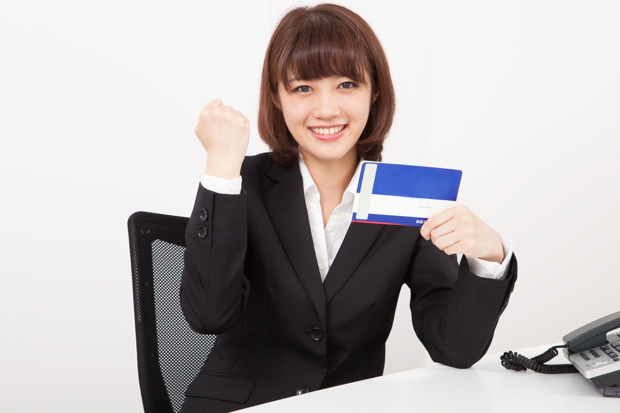貯金通帳を持ちガッツポーズをする女性