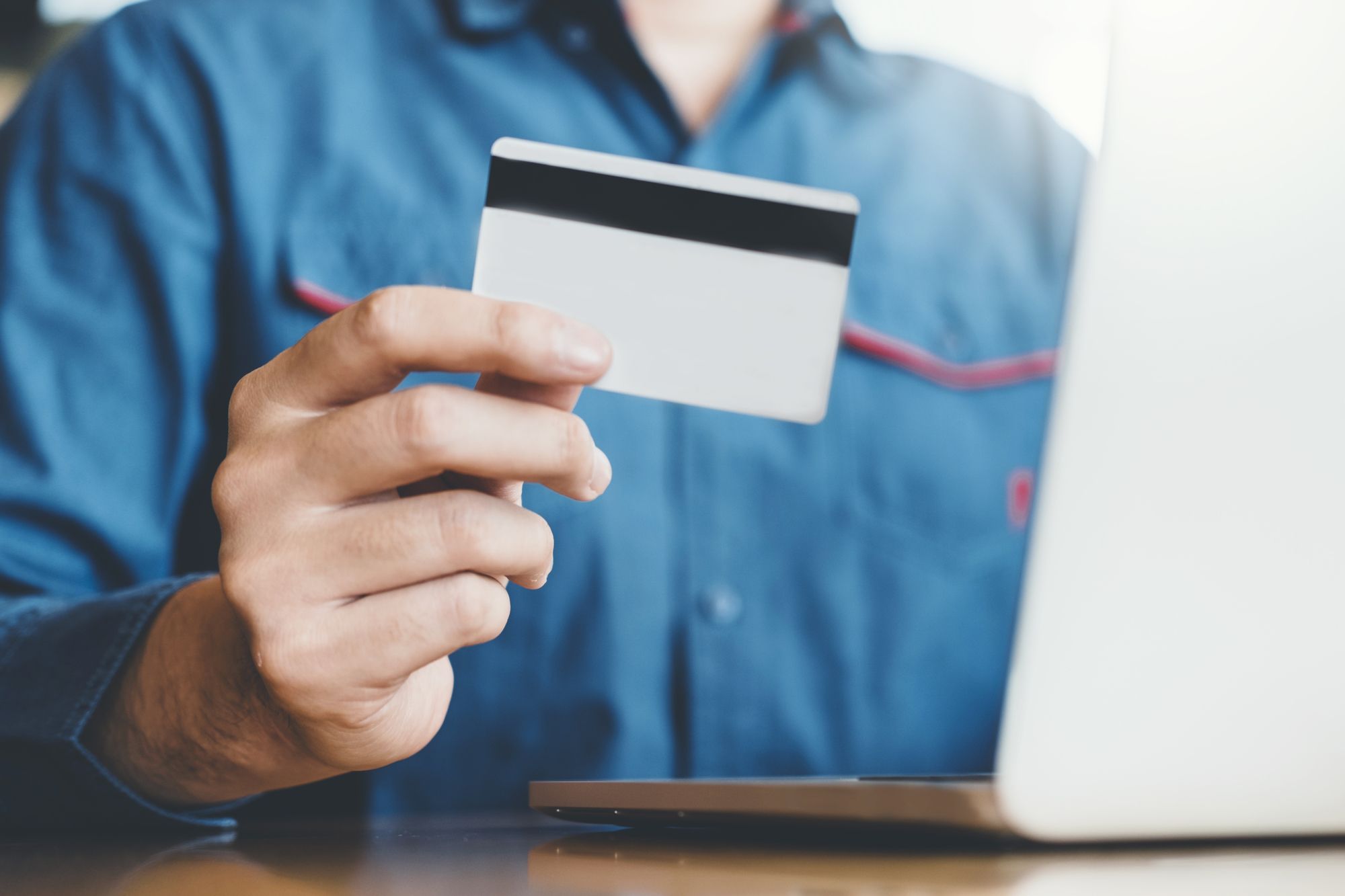 ノートパソコン前でクレジットカードを持つ男性