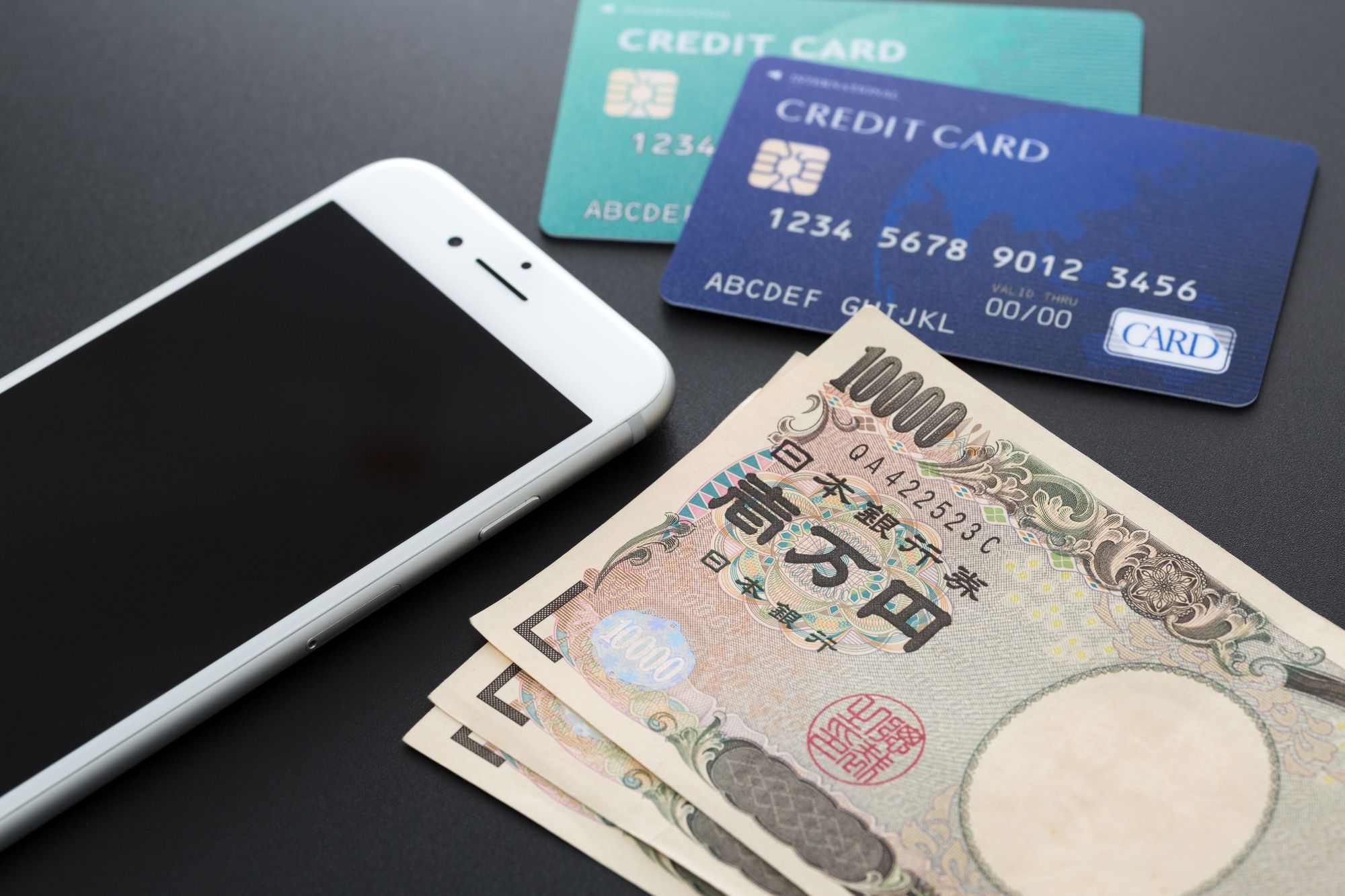 クレジットカードと現金とスマートフォンが置いてある