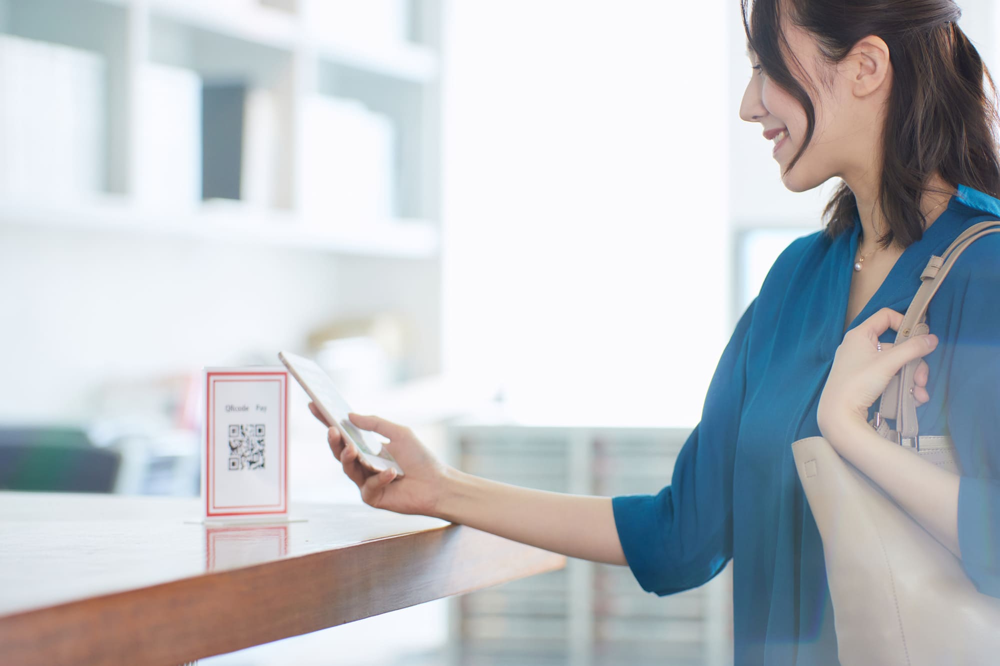 QRコードとスマホでキャッシュレス決済をする女性