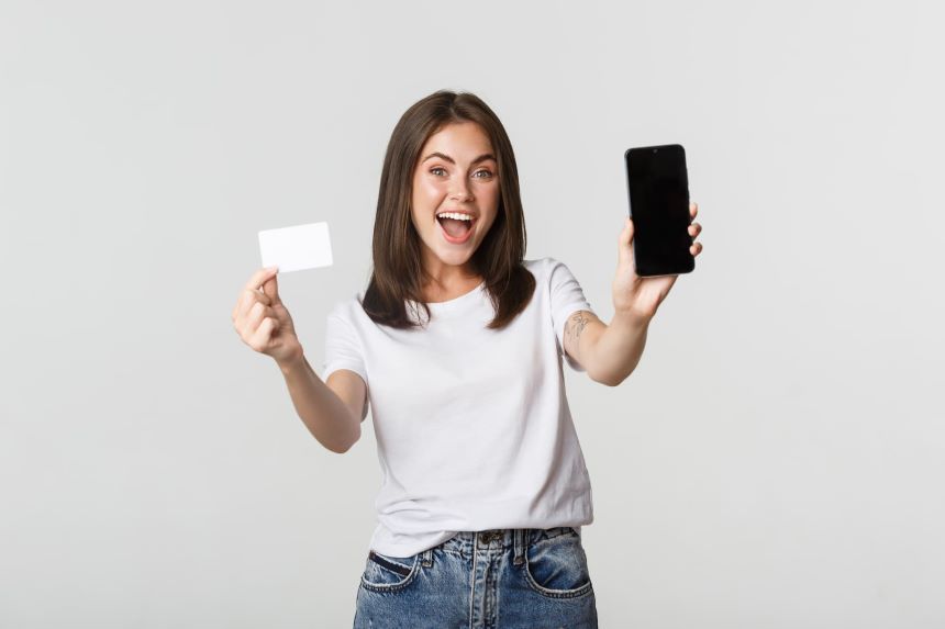 クレジットカードとスマホを持ち喜ぶ女性