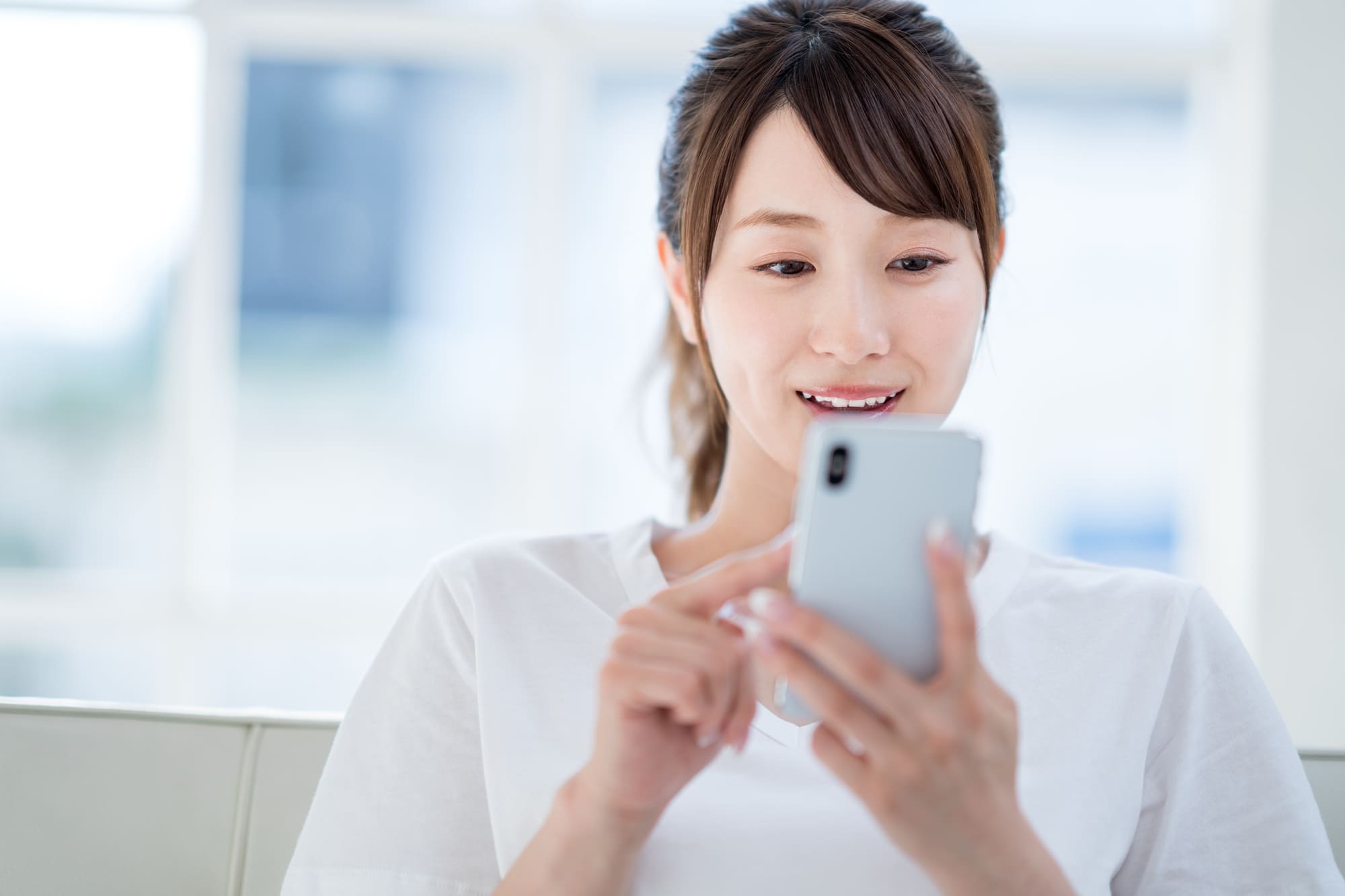 スマホ決済を調べる白いシャツの女性