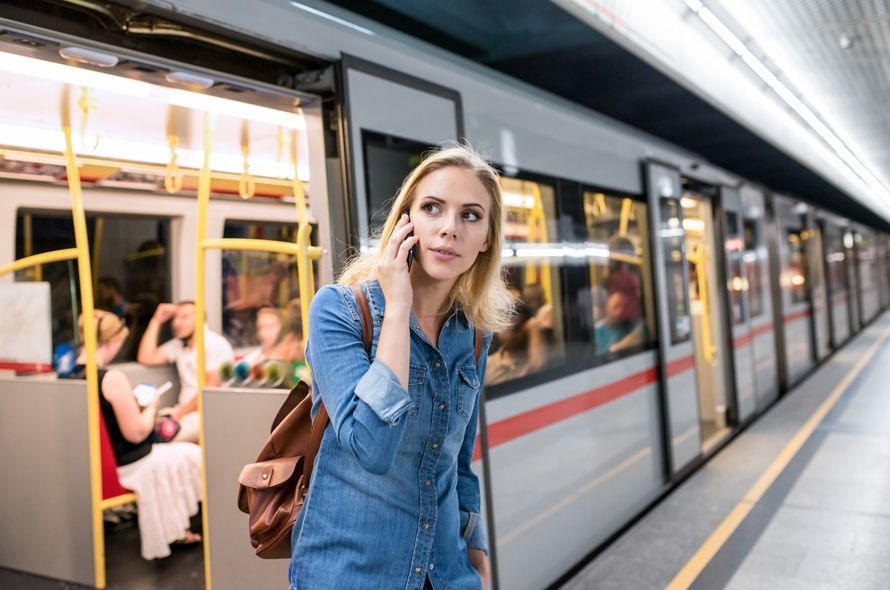 電車のホームで電話する女性