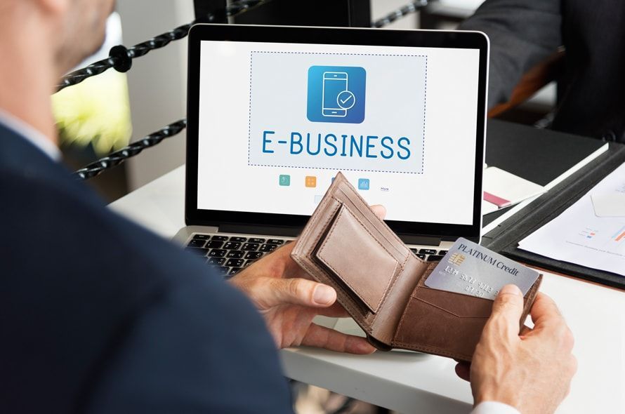 パソコンにE-BUSINESSの文字とサイフの中のクレジットカードを取り出す男性