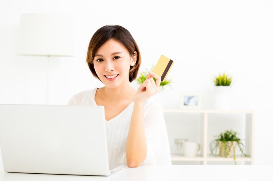 パソコンをしながらカードを持つ女性