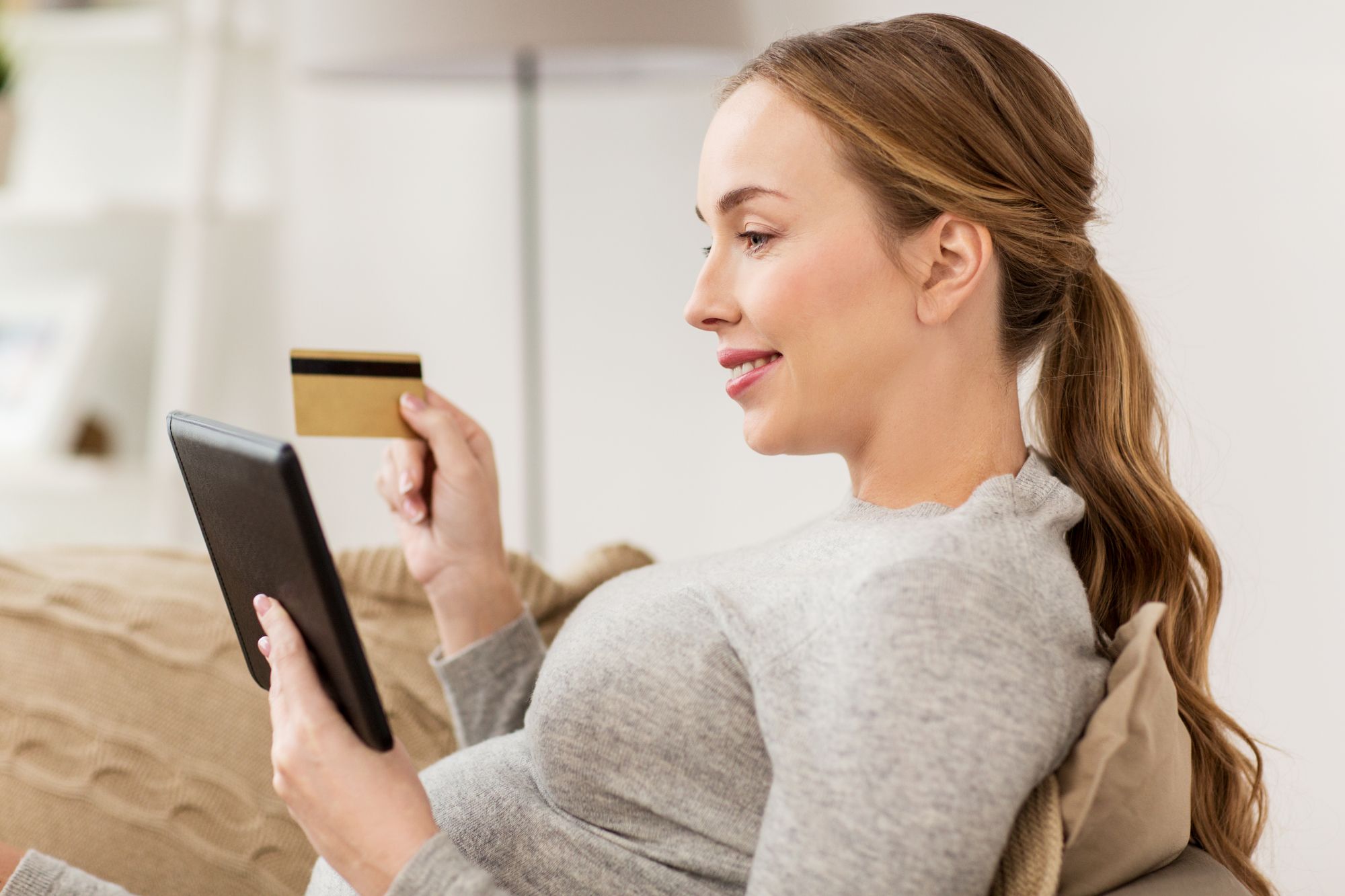 クレジットカードを持ちながらタブレットを見る女性