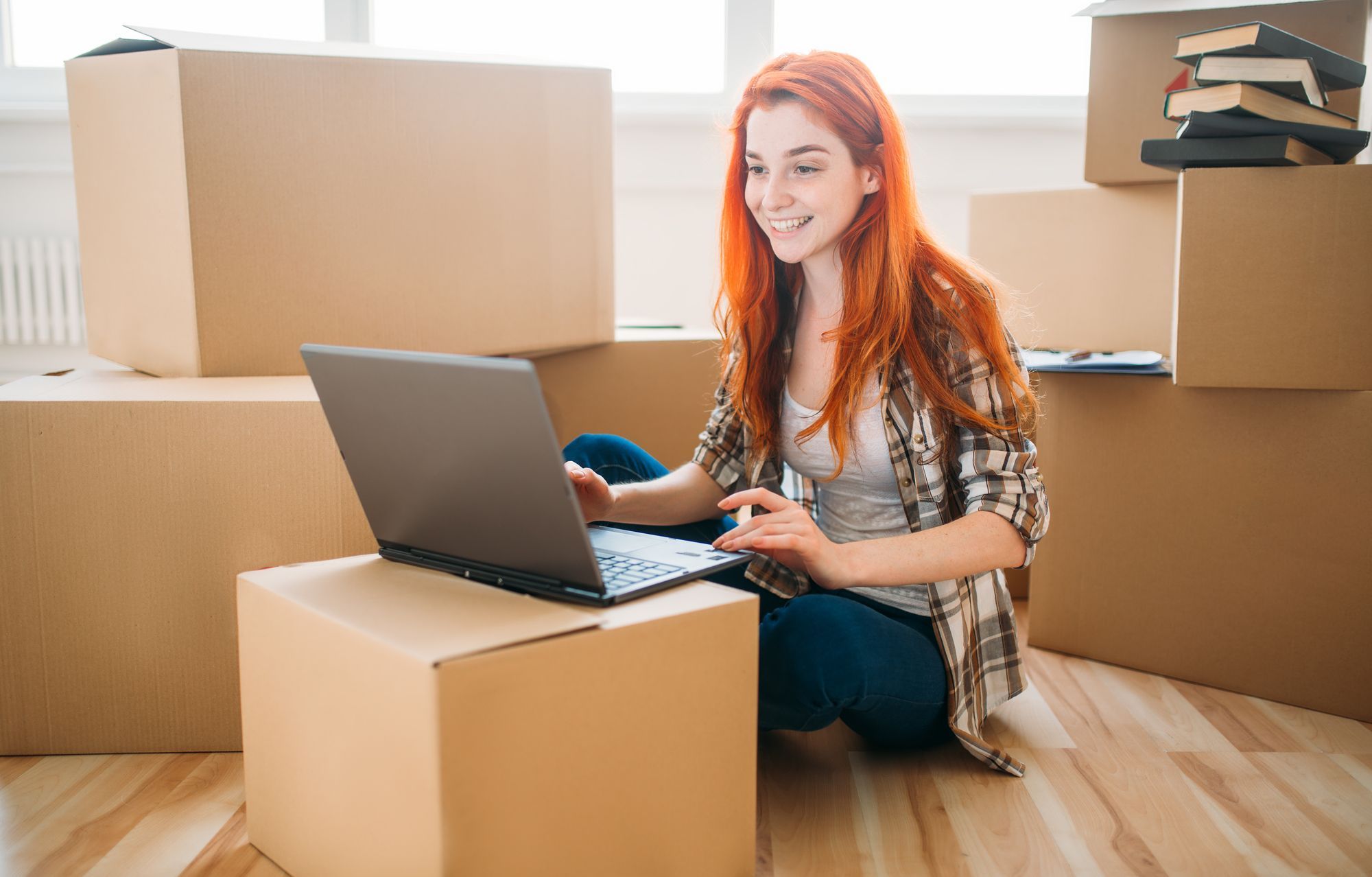 引越しのダンボールとノートPCを触る女性