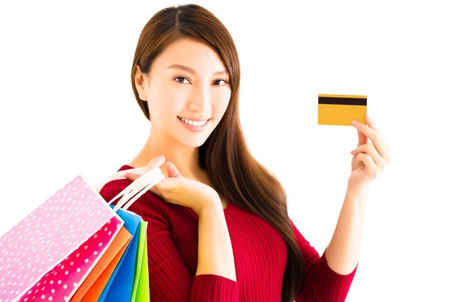買い物袋を持ちながらカードを持つ女性