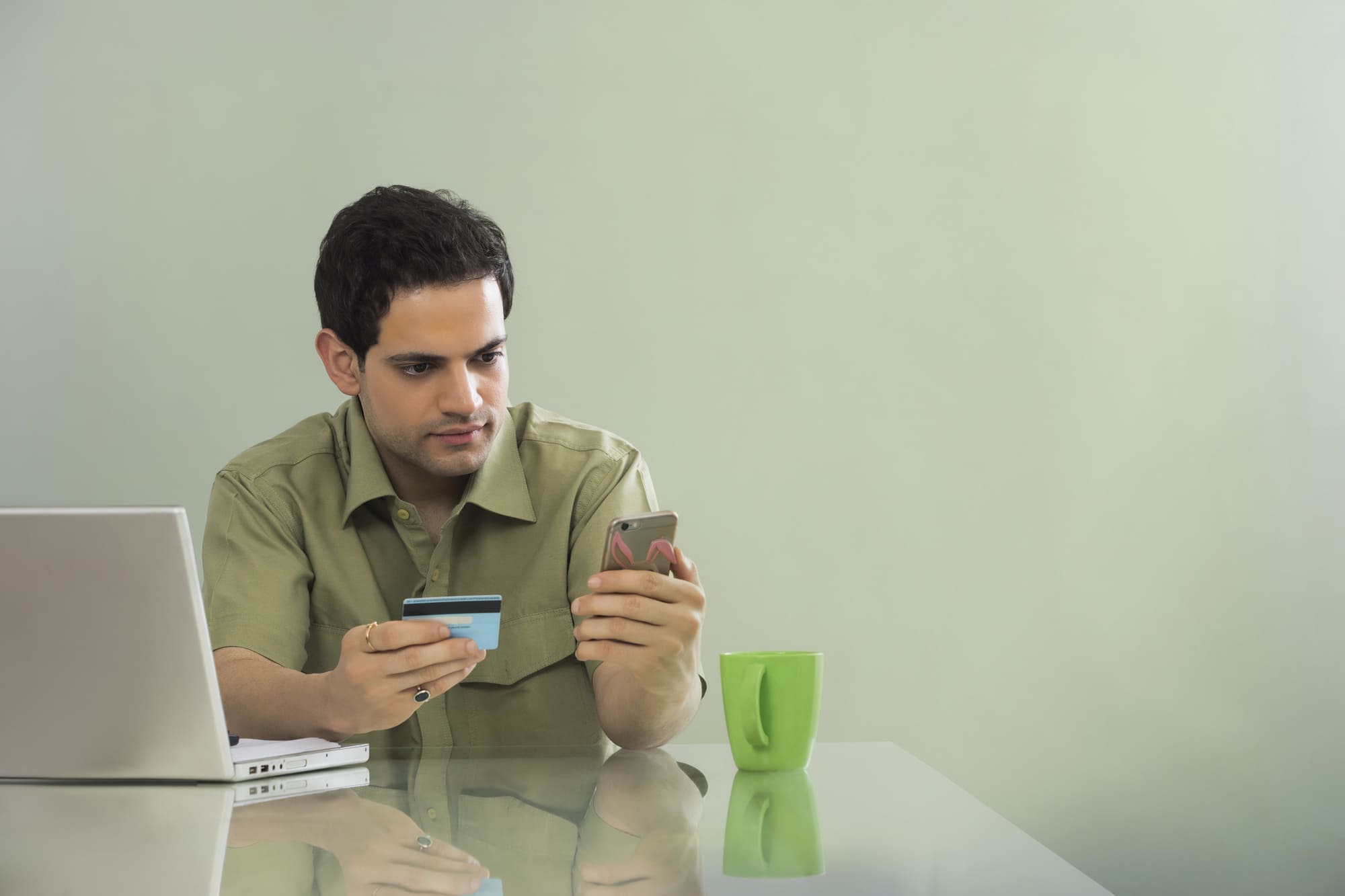 カードを手にもちスマホを見る男性
