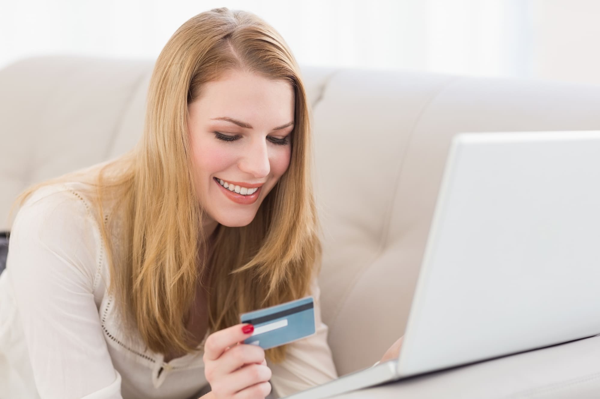 パソコンの前でクレジットカードを見て喜ぶ女性