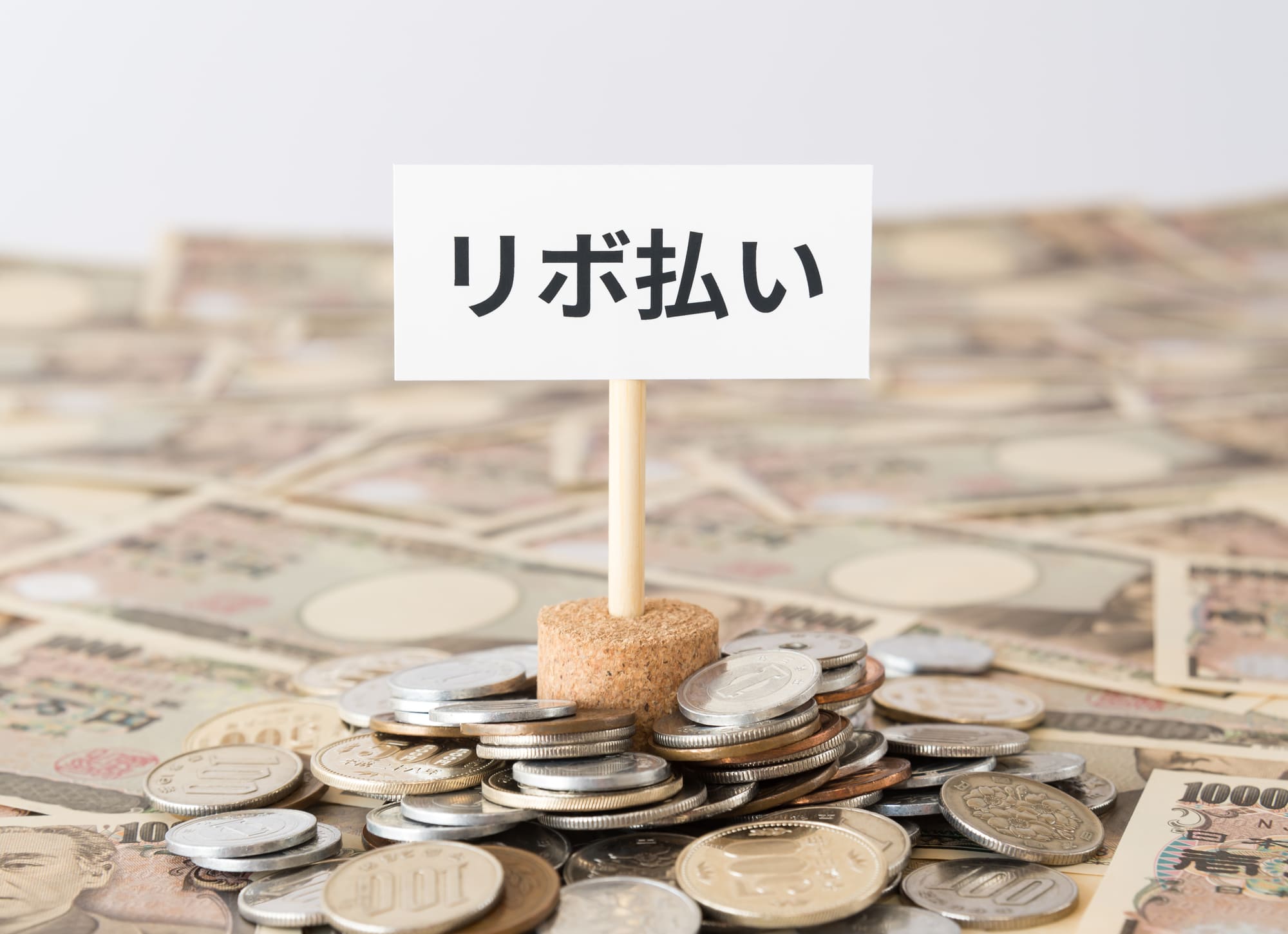 お金の上に「リボ払い」の旗