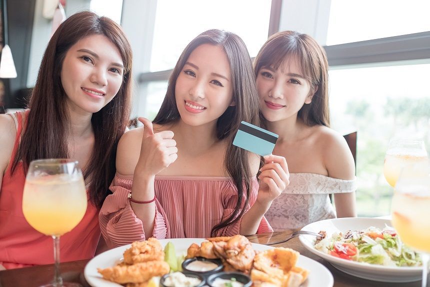料理を前にカードを手に微笑む3人の女性