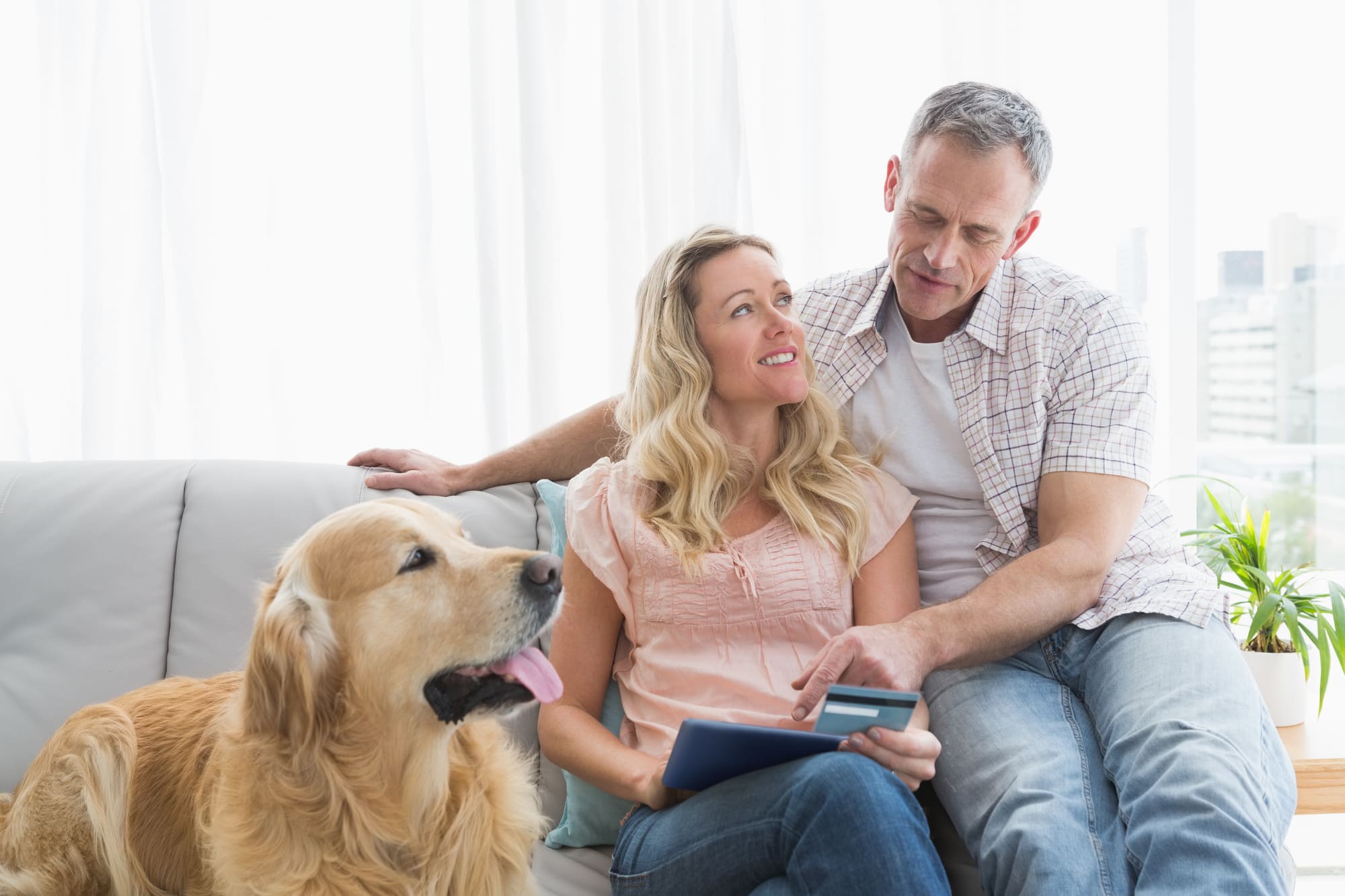 クレジットカードを見ながらパソコン操作をする夫婦と犬