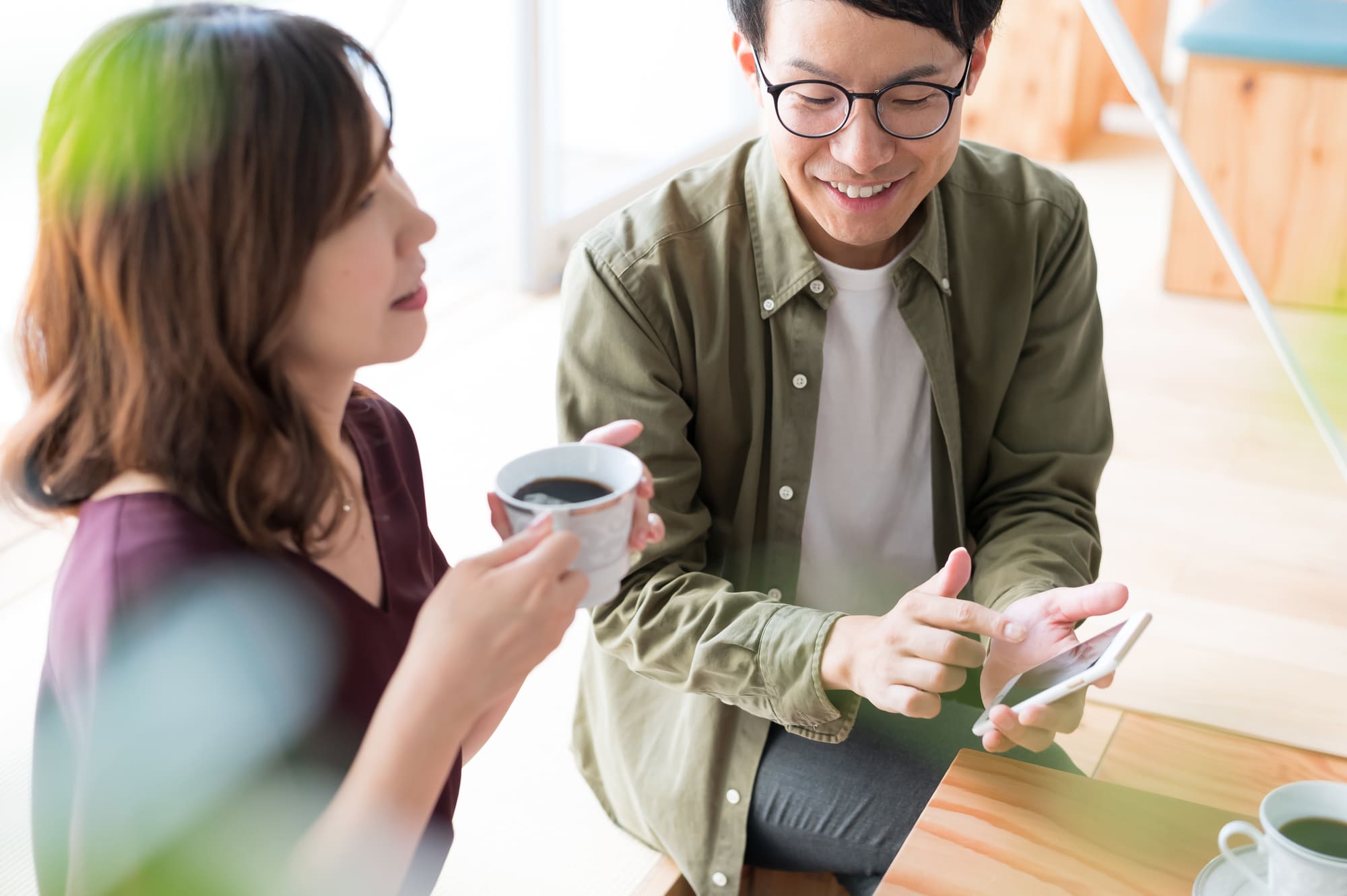 コーヒーを飲む女性とスマホを操作する男性