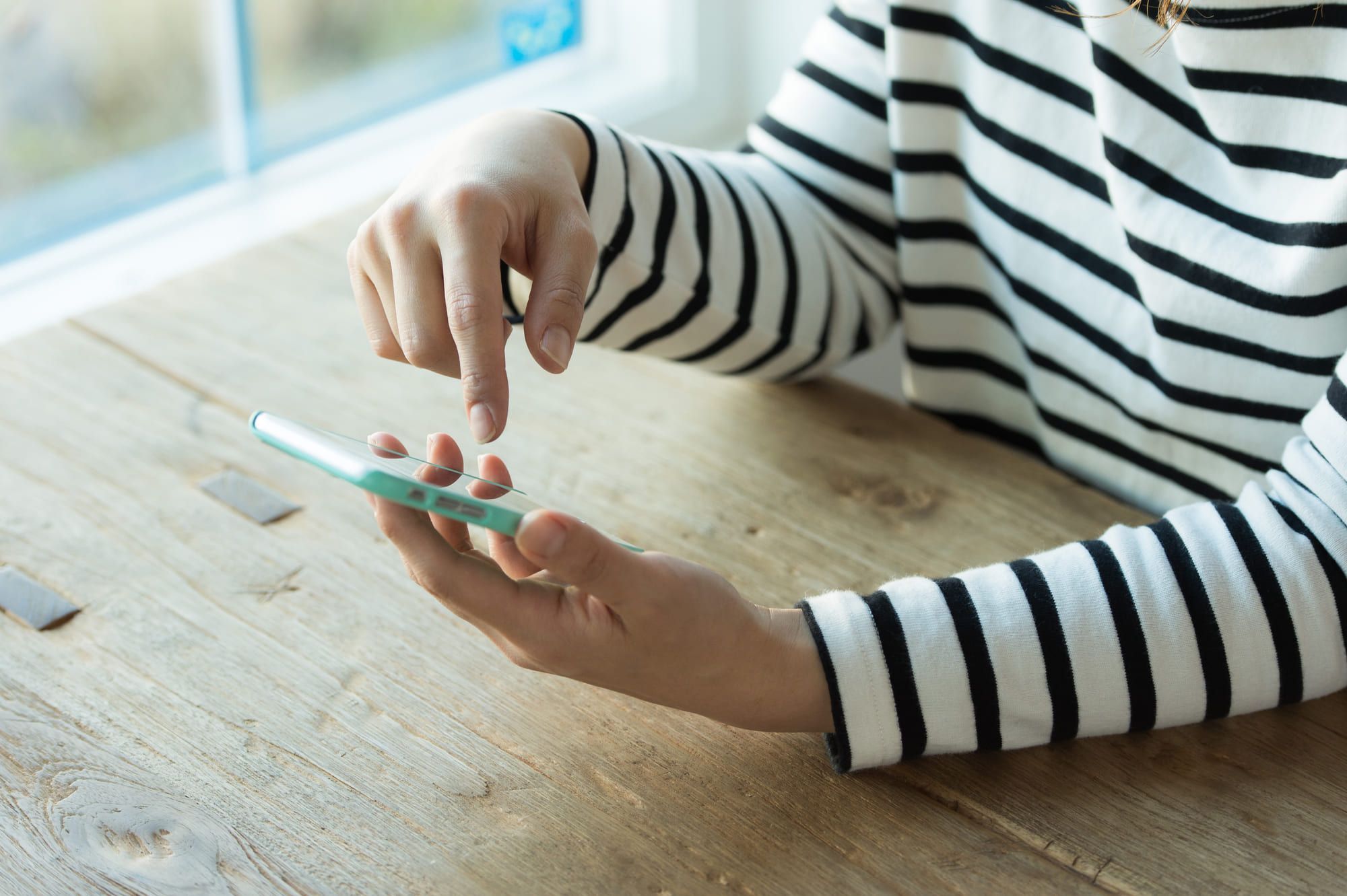 ボーダーのシャツを着てスマホを操作する手元