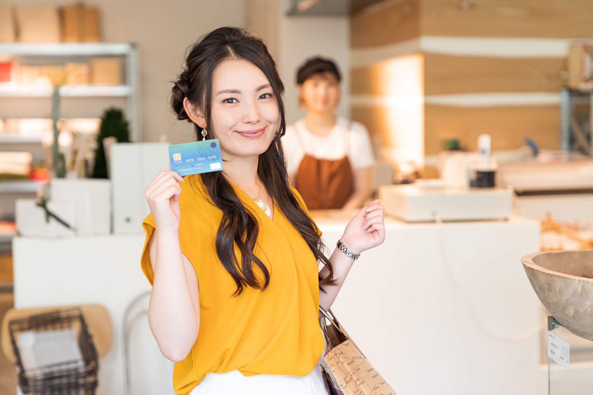クレジットカードで支払いをする黄色いブラウスを着た女性