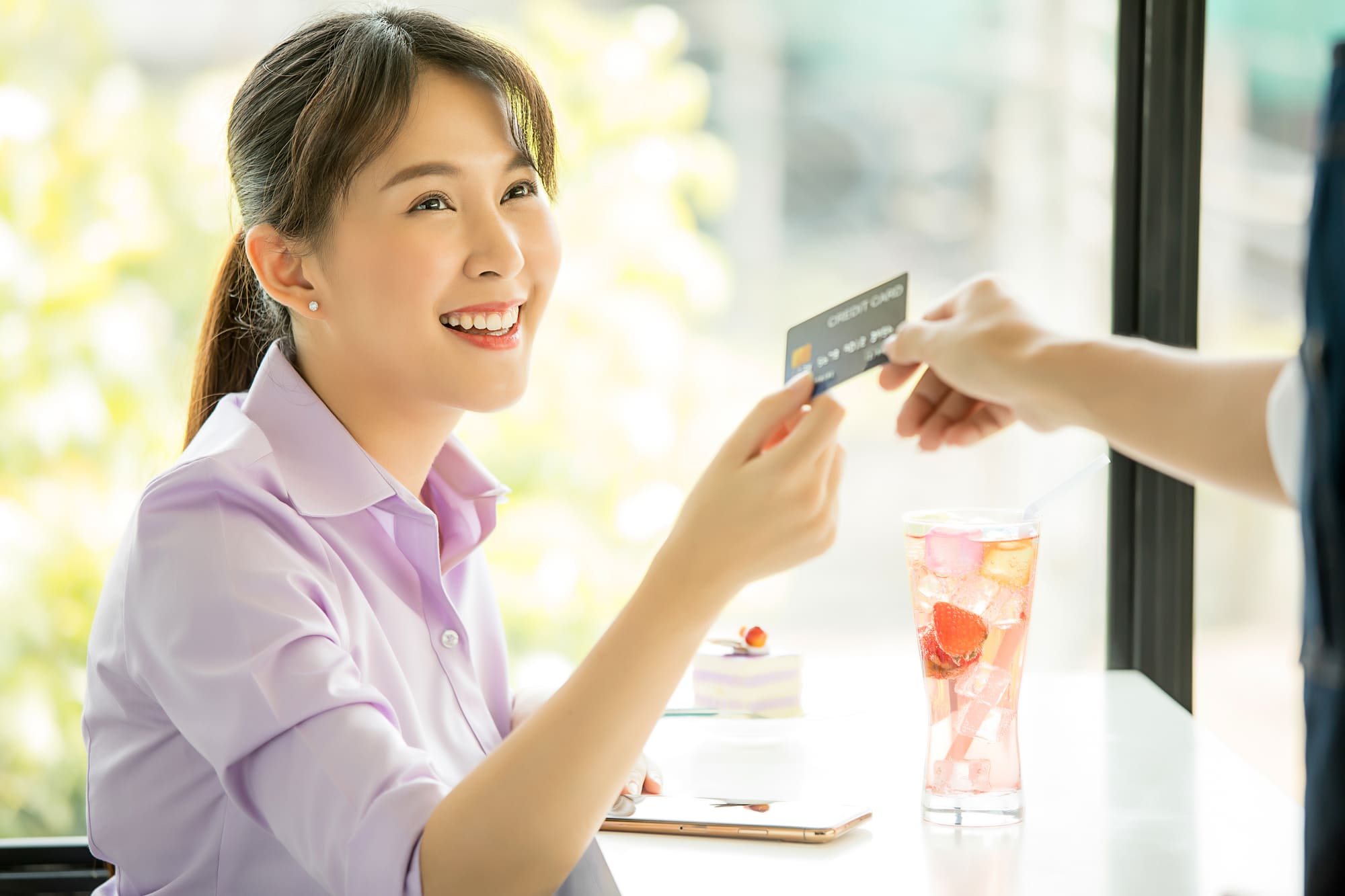 笑顔でクレジットカードを受け取る女性