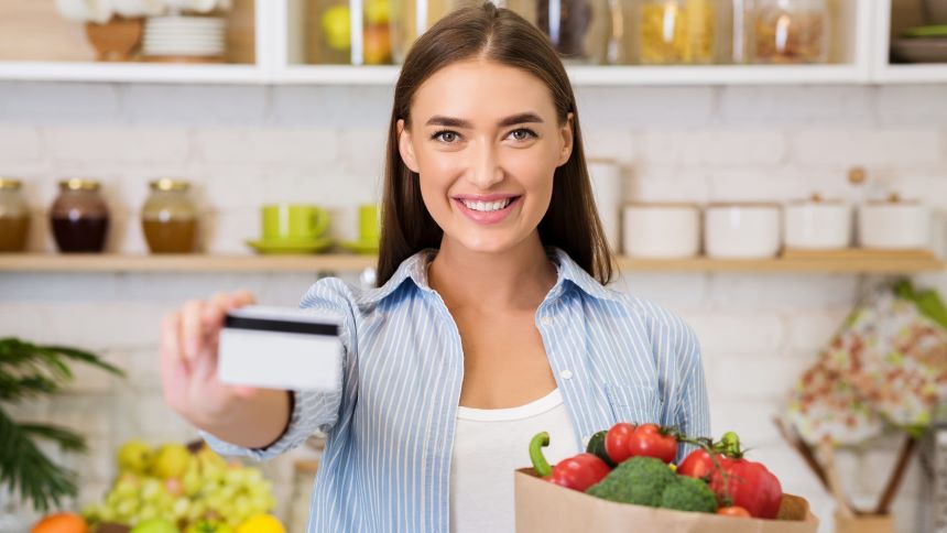 食品に囲まれてカードを見せる女性