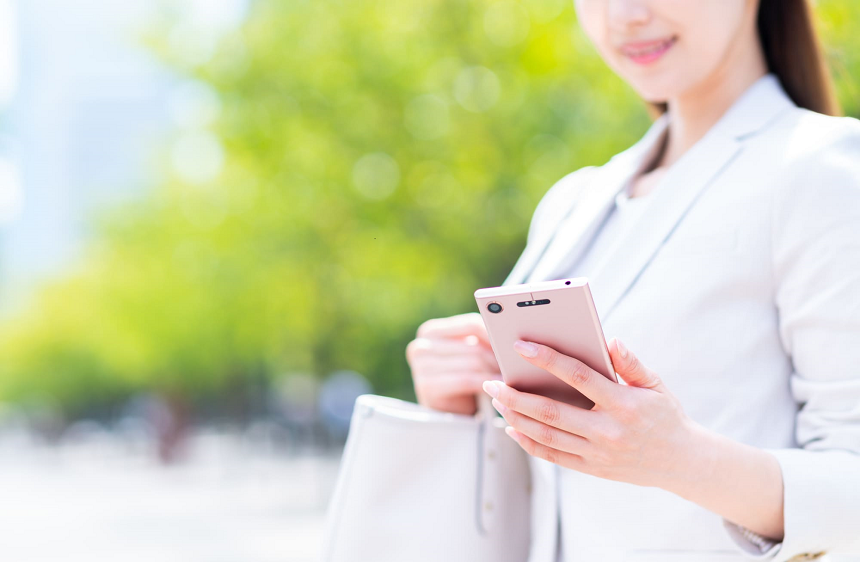 外出先でスマホを見ているスーツ姿の女性
