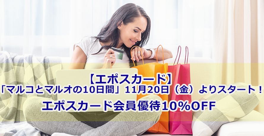 パソコン前でクレジットカードを持ちショッピングバックをのぞく女性