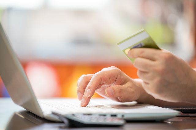 クレジットカードと照らし合わせながらパソコンを見ている